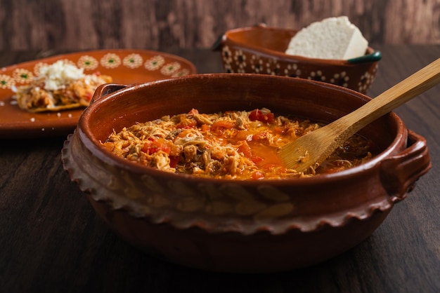 Autentico pollo messicano tinga tipico cibo messicano preparato in una pentola di argilla su un tavolo di legno