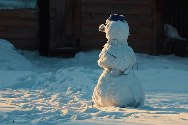 Autentico pupazzo di neve si trova nel villaggio al tramonto Inverno in campagna