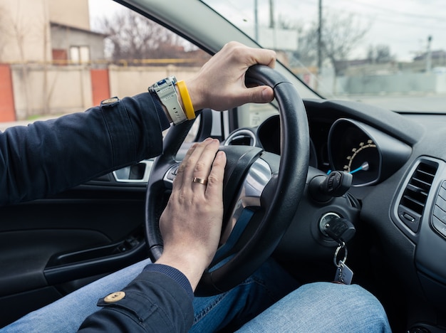 Autista dell'uomo nervoso che spinge il clacson, vista ravvicinata della mano sul volante