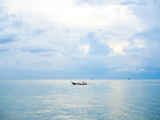 Autista di barche sulla tradizionale barca a coda lunga in mare con sfondo di nuvole e cielo al tramonto in stile minimalista Thailandia