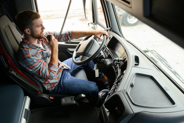 Autista di camion maschio che parla tramite il sistema radio CB nel suo veicolo