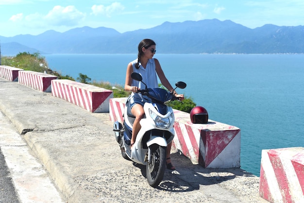 Autista di moto della giovane donna che si siede contro il mare della Cina del sud del sud nel vietnam