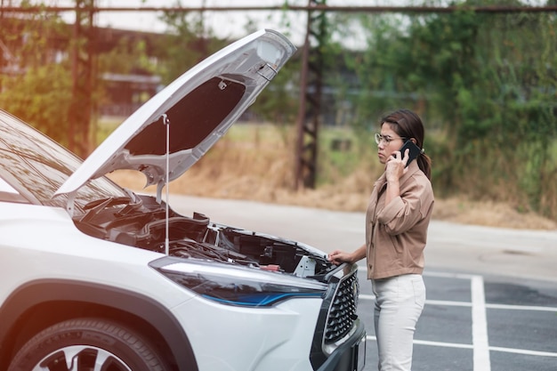 Autista donna che utilizza il telefono cellulare durante l'auto problematica Guasto o auto rotta su strada Concetto di manutenzione e servizio dell'assicurazione del veicolo