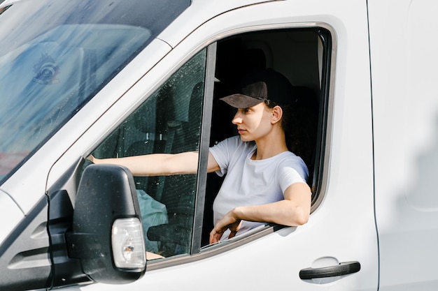 Autista donna in uniforme bianca alla guida di un furgone