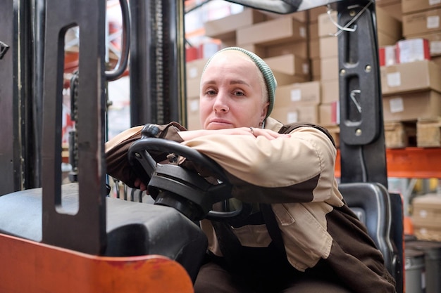 Autista femminile del carrello elevatore che lavora al magazzino