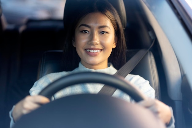 Autista femminile seduto e tenendo il volante con un sorriso di piacere