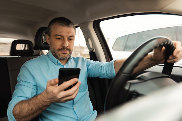 Autista maschio che utilizza smartphone per la navigazione alla guida di una nuova auto