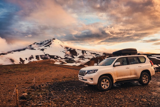 Auto a quattro ruote parcheggiata con montagna vulcanica e cielo al tramonto tra gli altopiani islandesi in estate a Kerlingarfjoll Islanda