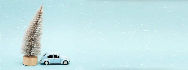 Auto blu in miniatura con un albero di natale su sfondo blu. striscione