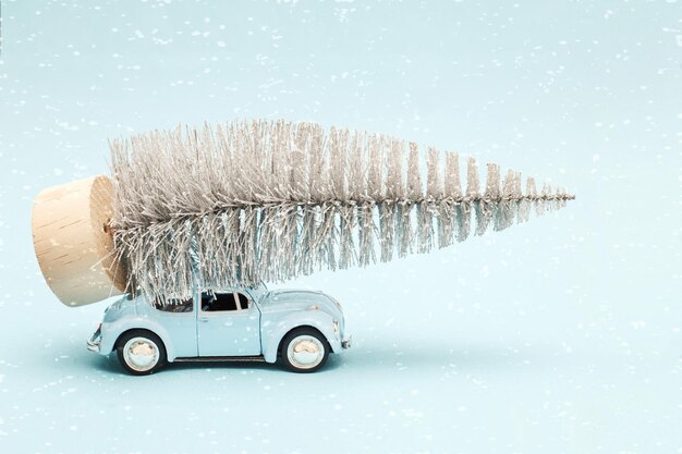 Auto blu in miniatura con un albero di natale sul tetto su sfondo blu.