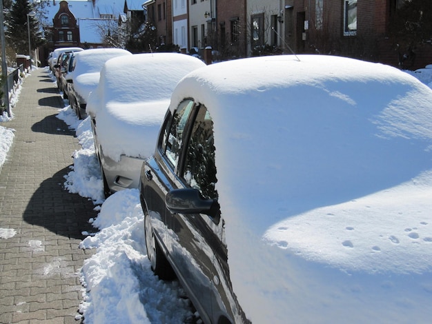Auto coperte di neve sulla strada durante una giornata di sole