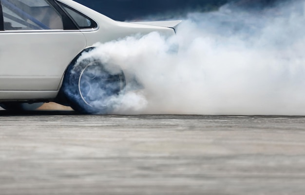 Auto da corsa che bruciano pneumatici sulla pista di velocità