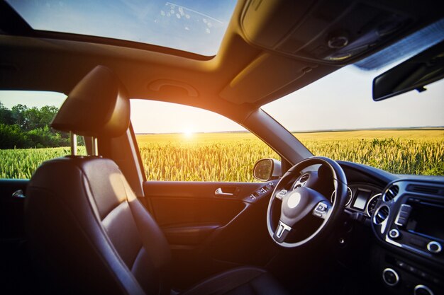 Auto di lusso all'interno degli interni. Volante, leva del cambio, salone in pelle, cruscotto e tetto panoramico. SUV crossover in campagna con il tramonto sullo sfondo.