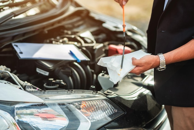 Auto di riparazione meccanica con cofano aperto Vista laterale del controllo meccanico del livello dell'olio motore in un'auto con cofano apertoControllare l'olio motore