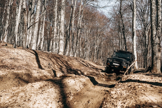 Auto fuoristrada che guida attraverso la strada forestale di fango