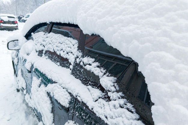 Auto parcheggiata coperta da uno spesso strato di neve dopo il primo piano invernale con messa a fuoco selettiva
