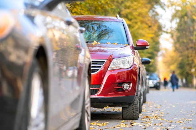 Auto parcheggiate in fila su un lato di una strada cittadina in una luminosa giornata autunnale.