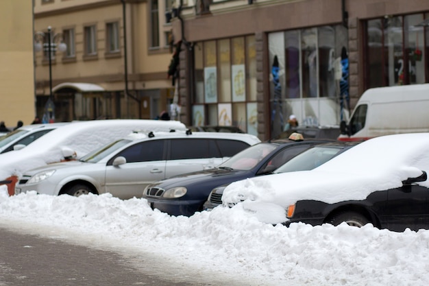 Auto parcheggiate su un lato della strada cittadina ricoperta di neve in inverno.