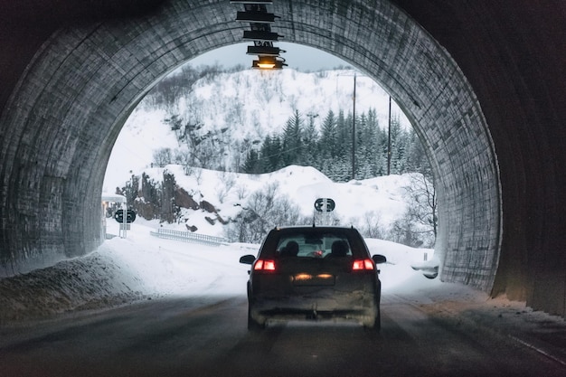 Auto posteriore che guida nel tunnel di montagna in inverno nevoso