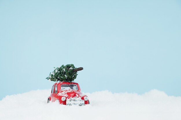 Auto rossa di Capodanno con albero di Natale in un paesaggio innevato