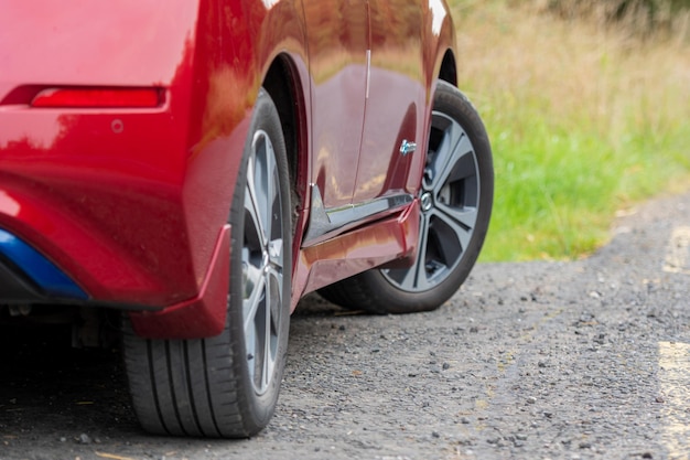 Auto rossa. Le ruote dell'auto si chiudono su uno sfondo di asfalto.