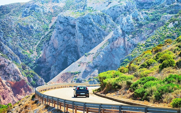 Auto su strada con colline e montagne idilliache a Buggerru a Carbonia-Iglesias, Sardegna, Italia