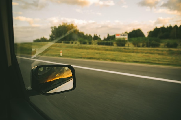 Auto sul tramonto dell'autostrada nella riflessione dello specchio dell'auto