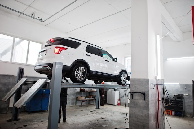 Auto SUV americana su supporto per il controllo del camber di allineamento delle ruote nell'officina della stazione di servizio