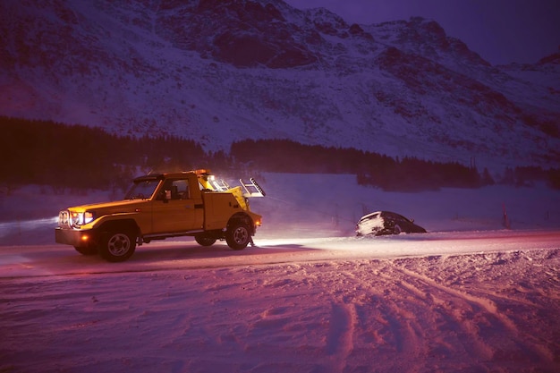 Auto trainata dopo un incidente durante una tempesta di neve su una strada ghiacciata scandinava durante una fredda notte invernale