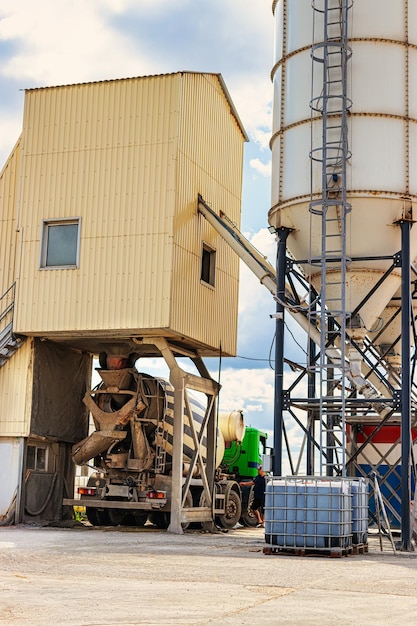 Autobetoniera davanti a un impianto di betonaggio cementificio Carico autobetoniera Primo piano Consegna del calcestruzzo al cantiere Opere monolitiche in calcestruzzo