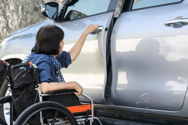 Automobile anziana della porta aperta della donna