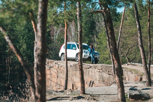 Automobile bianca del suv alla donna giovane della scogliera rocciosa vicino esso