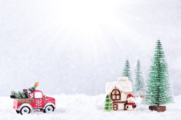 Automobile che trasporta l'albero di Natale alla casa di campagna su sfondo argento con fiocchi di neve