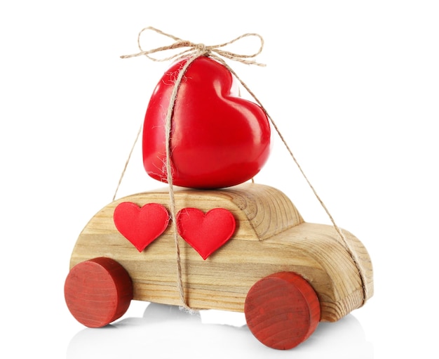 Automobile di legno con un cuore rosso legato ad esso isolato su bianco