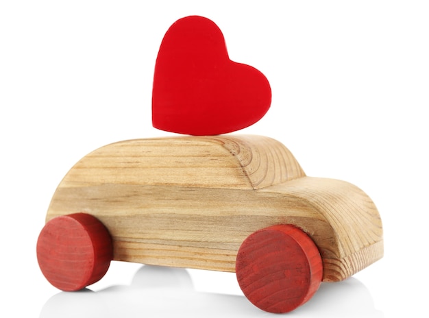 Automobile di legno con una piccola figura rossa del cuore isolata su bianco