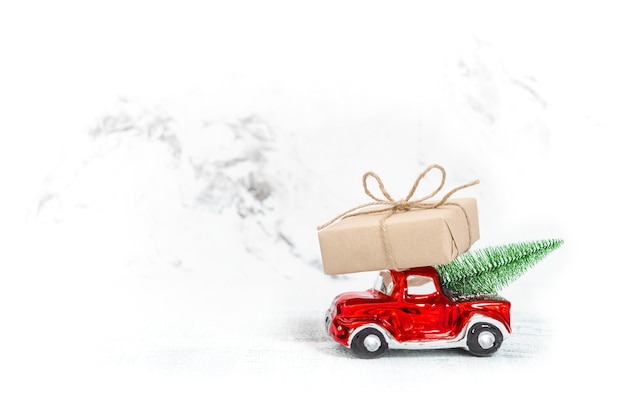 Automobile rossa con scatola regalo e albero di Natale. Copia spazio