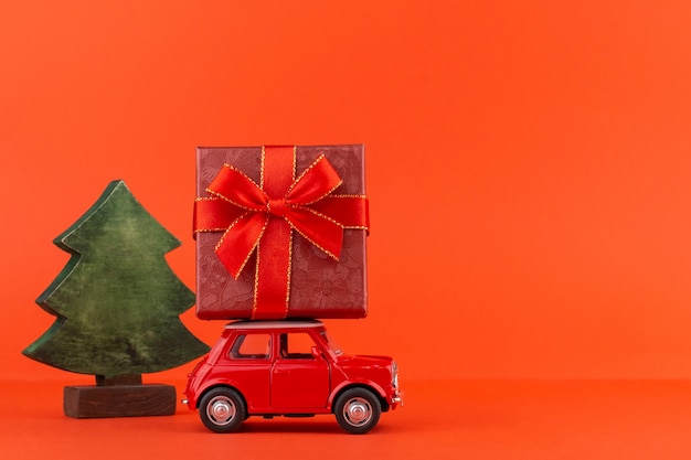 Automobile rossa del giocattolo con un albero di natale e una confezione regalo sul tetto