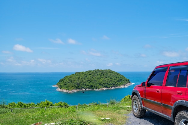 Automobile rossa SUV 4x4 sulla montagna con mare estivo e sfondo di una piccola isola di spazio libero per testo estivo e sfondo del trasporto di viaggio.