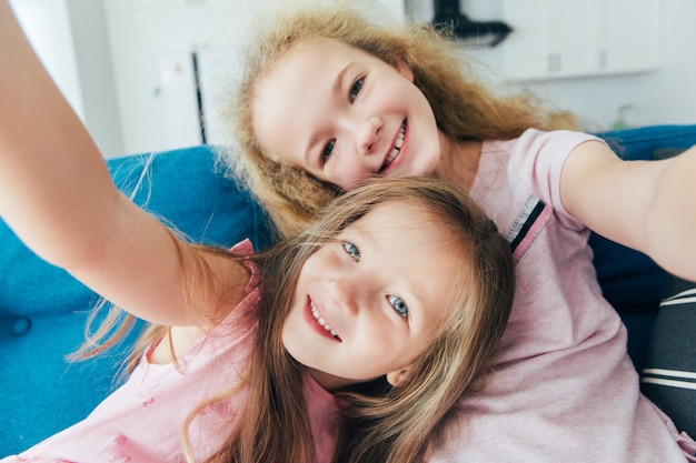 Autoritratto di sorelle pazze e sciocche, ridendo, facendo selfie insieme sul cellulare a casa