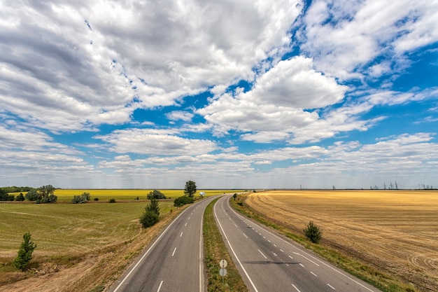 Autostrada che passa attraverso i campi contro un cielo azzurro con belle nuvole bianche