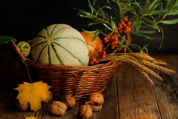 Autunno ancora in vita con il melone in una chiave scura su uno sfondo di legno