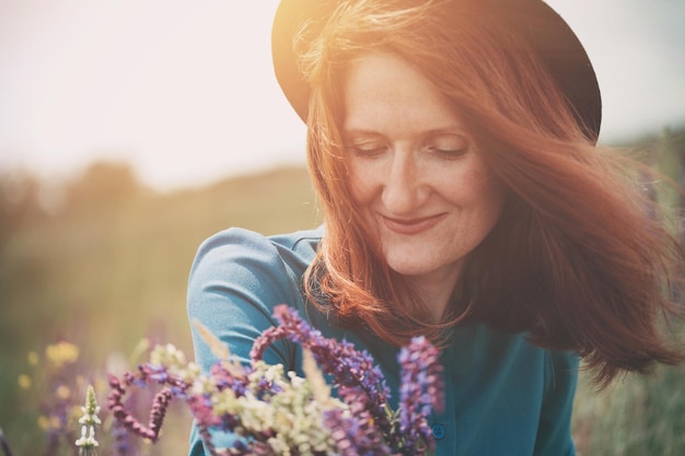 Autunno - bella ragazza su un prato con un mazzo di fiori di campo