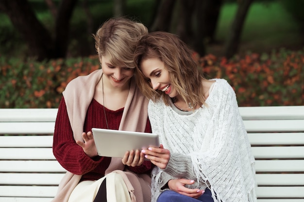 Autunno bello delle ragazze delle donne facendo uso della compressa all'aperto