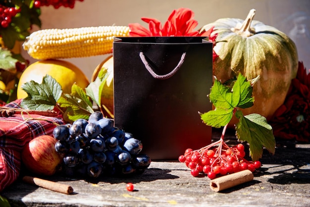 Autunno creativo mock up di sacchetto regalo tra frutta e verdura zucca mais pere uva viburno e melone Giorno del Ringraziamento concetto Autunno estetico natura morta con ombre alla moda