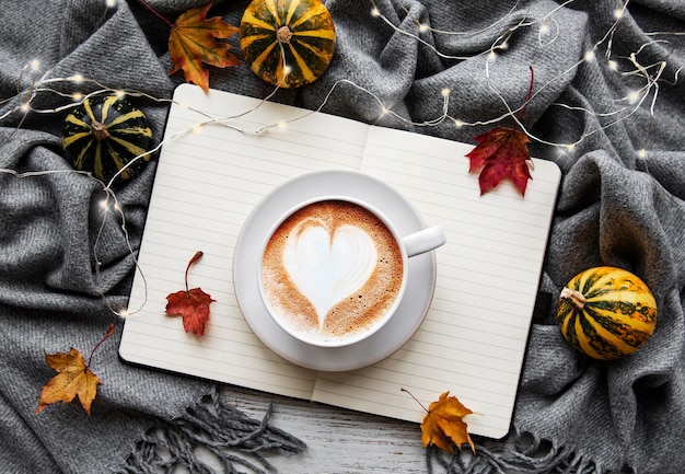 Autunno distesi con una tazza di caffè, foglie, zucca e coperta calda