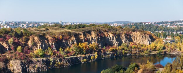 Autunno dorato con alberi colorati nella vecchia cava allagata. Rocce, lago e alberi gialli