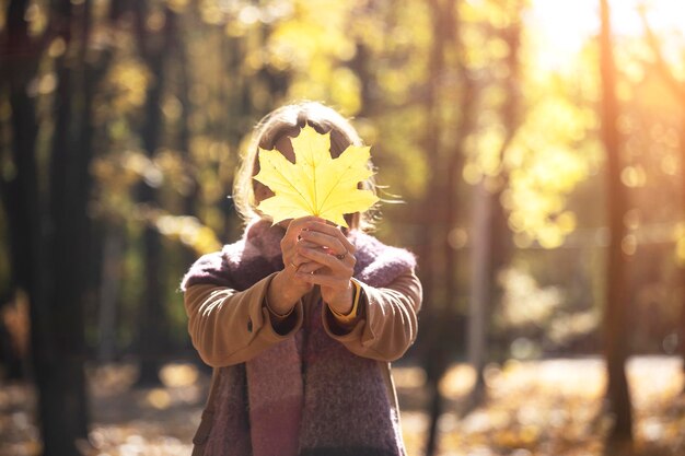 Autunno - la ragazza divertente tiene una foglia gialla