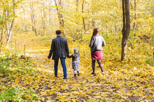 Autunno, natura e concetto di famiglia - famiglia che cammina nel parco autunnale, vista posteriore