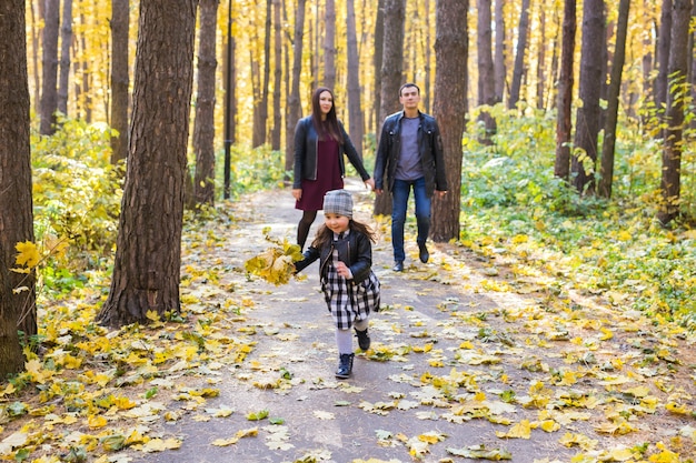 Autunno, natura e concetto di famiglia - famiglia felice che cammina nel parco autunnale