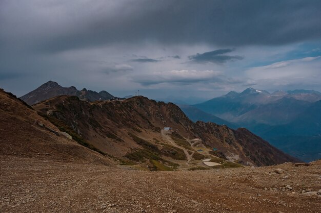 Autunno nel Caucaso settentrionale, località sciistica di Rosa Khutor in bassa stagione. Russia, Soci. Tonificazione vintage. Sfondo di viaggio. Cielo drammatico, ora del tramonto, belle nuvole pesanti.